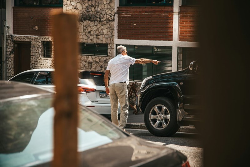 Man standing next to a parked black truck while pointing