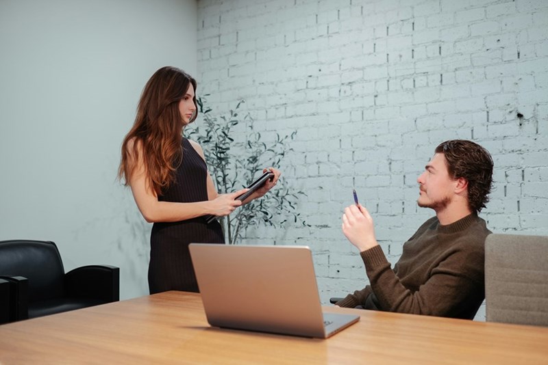A well dressed woman talks her boss sitting in a chair