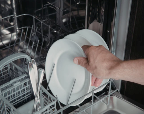 Loading the dishwasher with a few dishes before launching a new wash cycle.