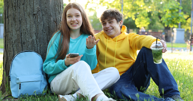 Teenagers hanging out at the park on a sunny day.