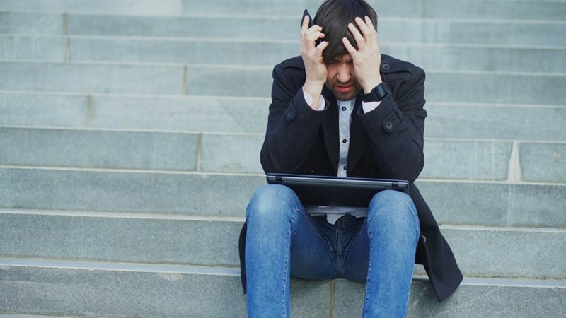 A man sits on steps with his head in his hands