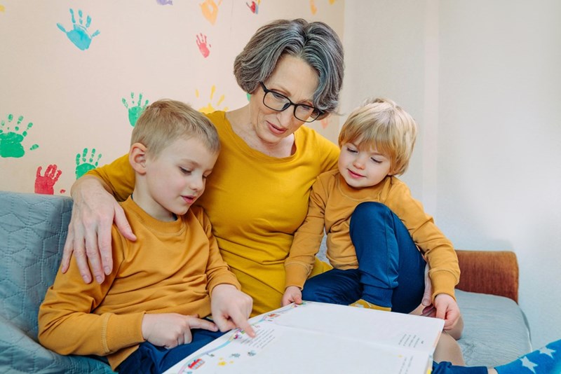 Grandma reads to her grandchildren while they wear matching yellow clothes.