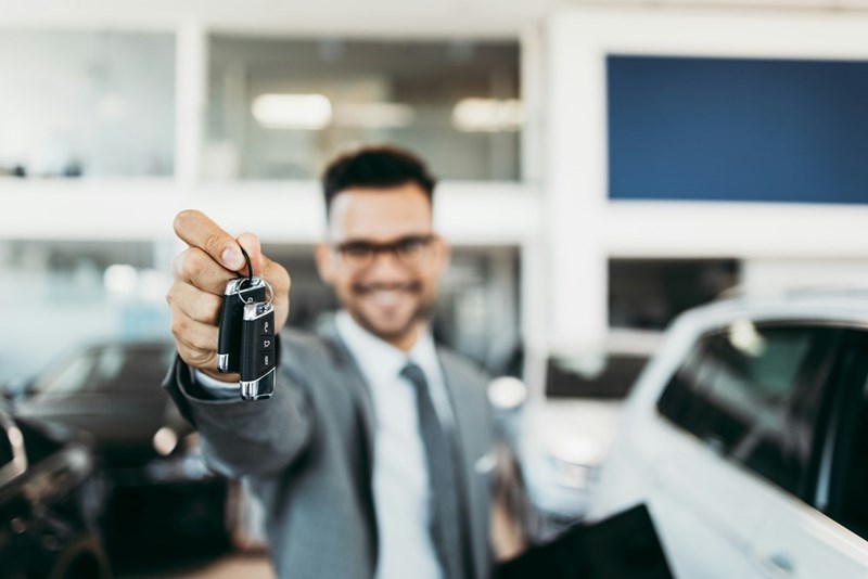 A car dealership worker holds up car keys