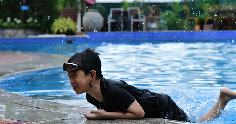 Boy having fun swimming in the neighbor's pool.