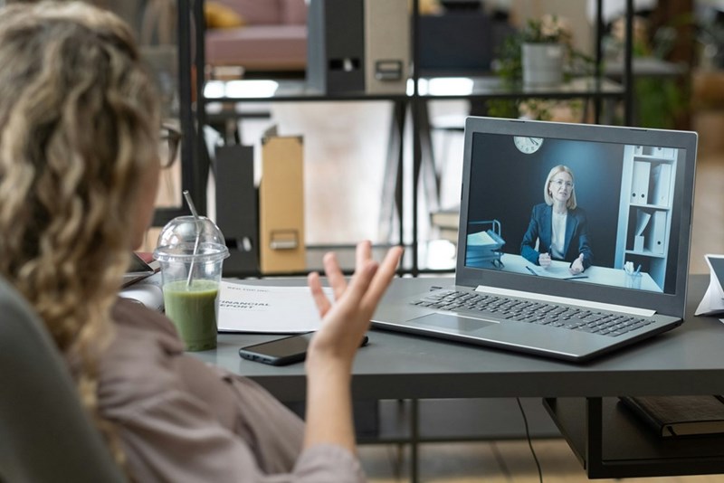 An employee gestures toward the camera while talking with their boss on a video phone call