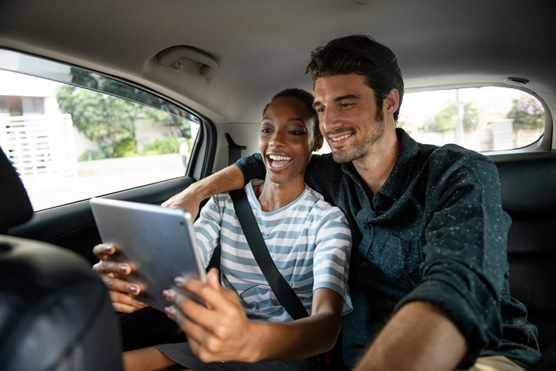 Two friends take an iPad selfie in the backseat of their Uber while on their vacation.
