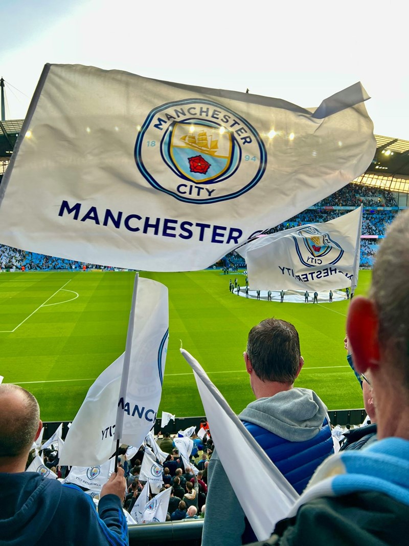 A group of people holding Manchester City flags
