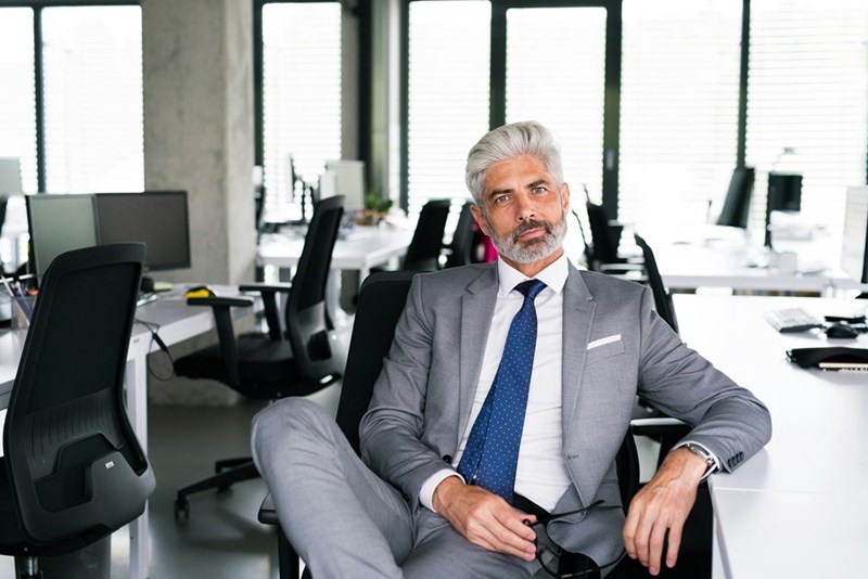 Mature businessman in gray suit sitting at desk in the office