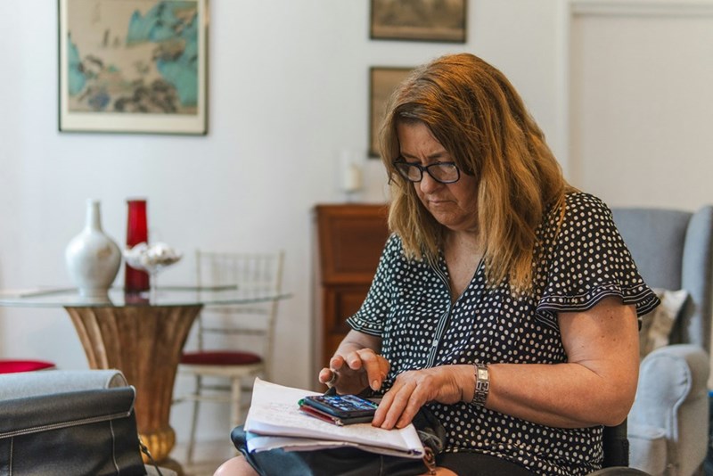 Woman using a calculator with papers on the table.