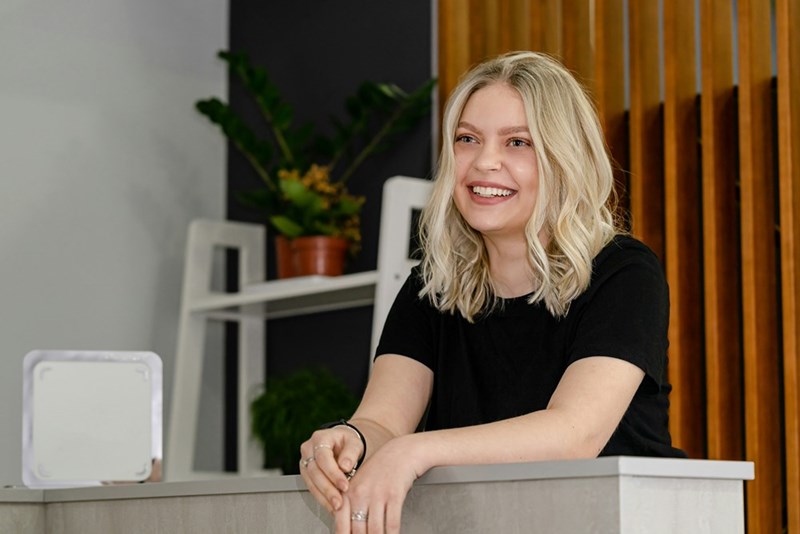 Attractive Caucasian woman smiling at reception desk in beauty salon