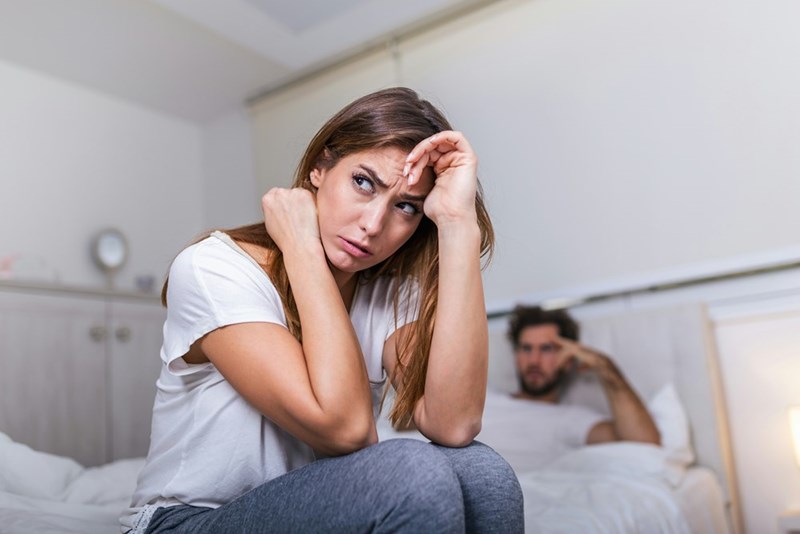 A frustrated woman sits on the edge of the bed