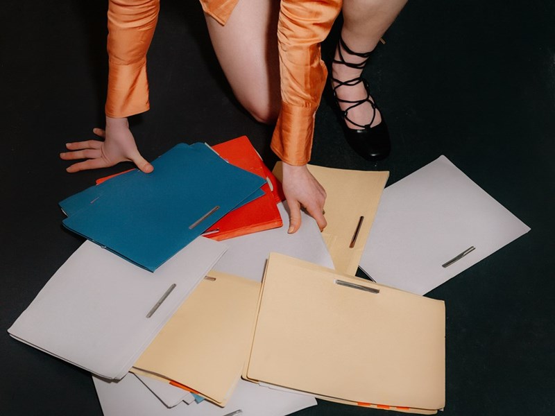A person reaching for papers and files on the floor