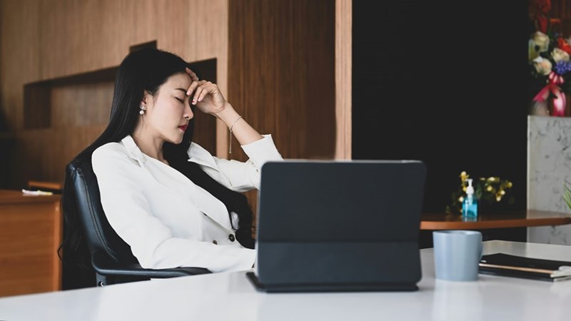 A young businesswoman holds her head in her hands at her desk