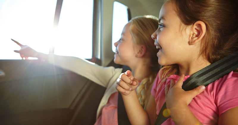 Two little girls in the backseat of a car.