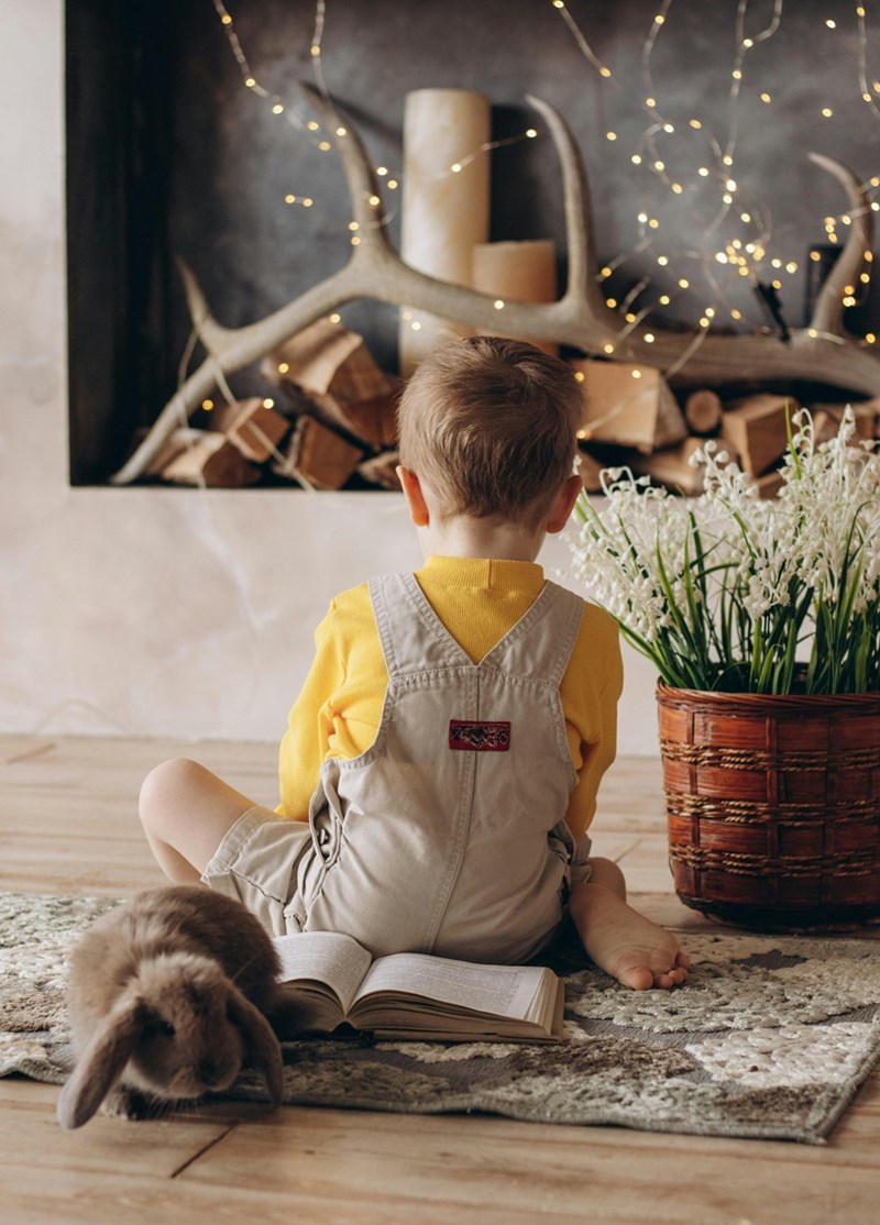 Young boy sits in a corner of a house and eats his easter egg by himself