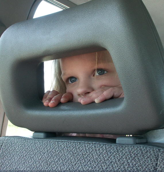 Little girl looking towards the front of the car on her way to school.