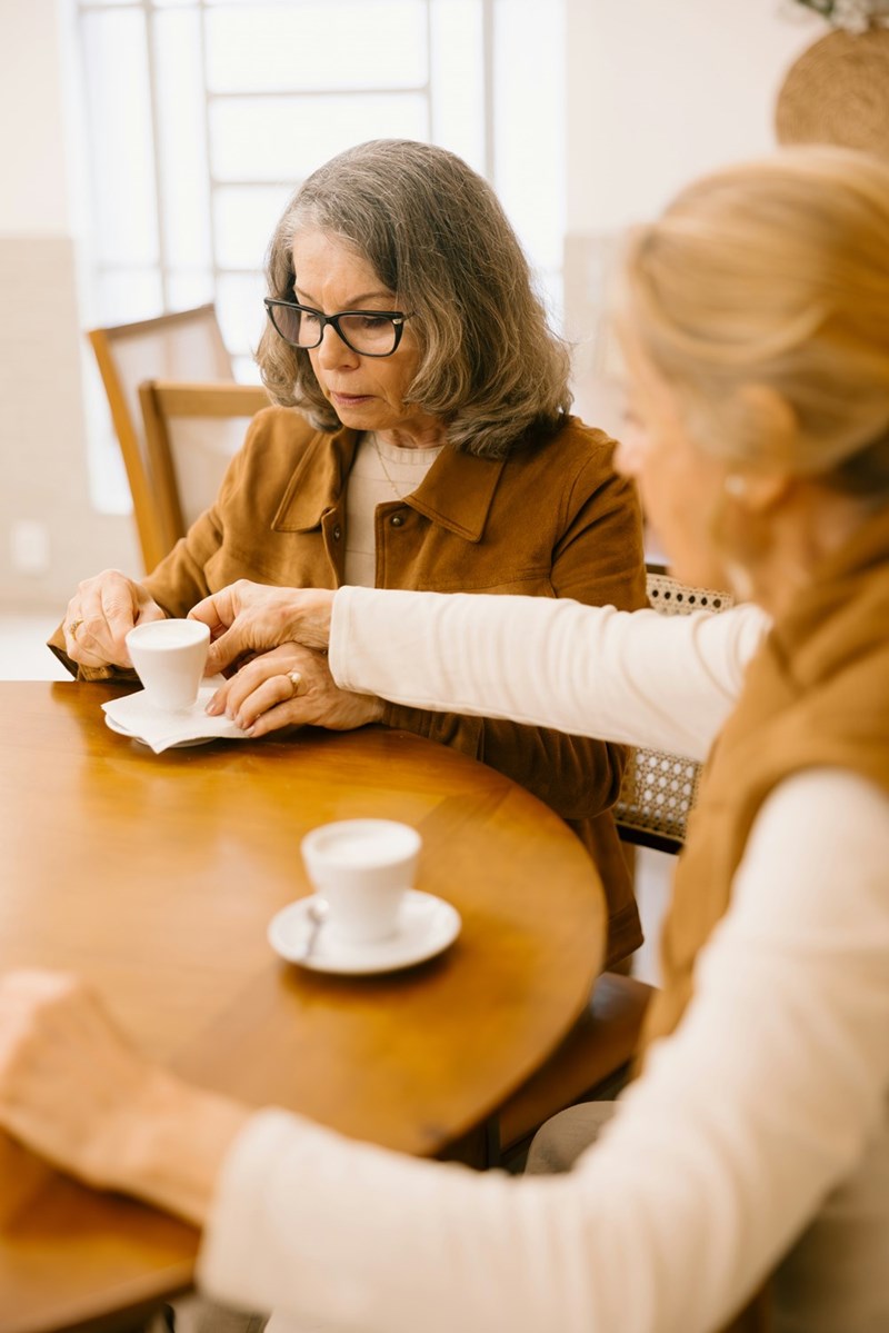 Old woman is sitting at a table while she discusses with her daughter-in-law