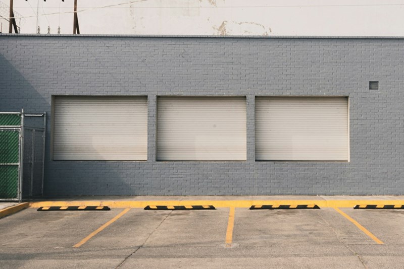 An empty row of parking spaces lined up against a plain brick wall.