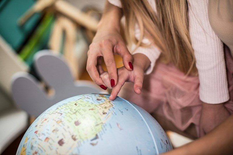 Grandma helps grandkid point to a place on the globe, teaching kids geography and astronomy