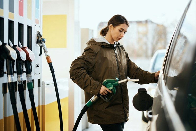 Young woman refueling the gas tank of her car at gas station
