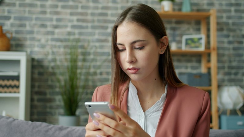 A young woman looks at her phone, frustrated