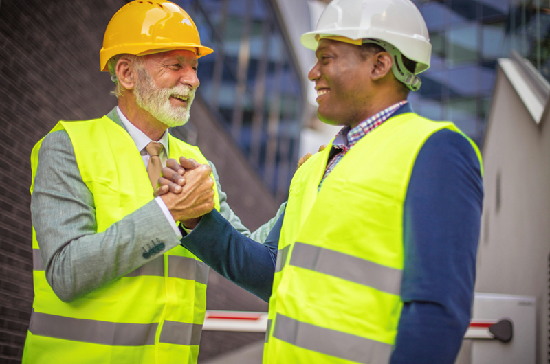 Old worker and middle-age worker unite on construction site to work together.