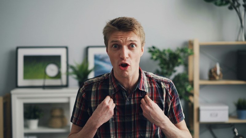 A man makes a surprised face in a living room