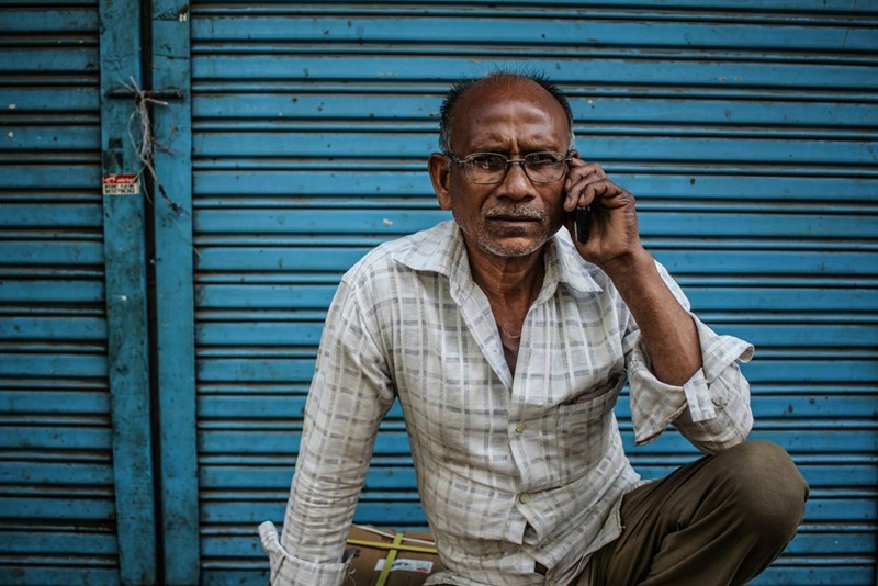 Sitting man wearing gray shirt holding phone on ear