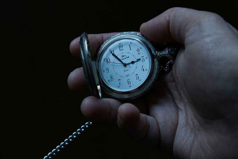 A person holds an analog watch in their hands