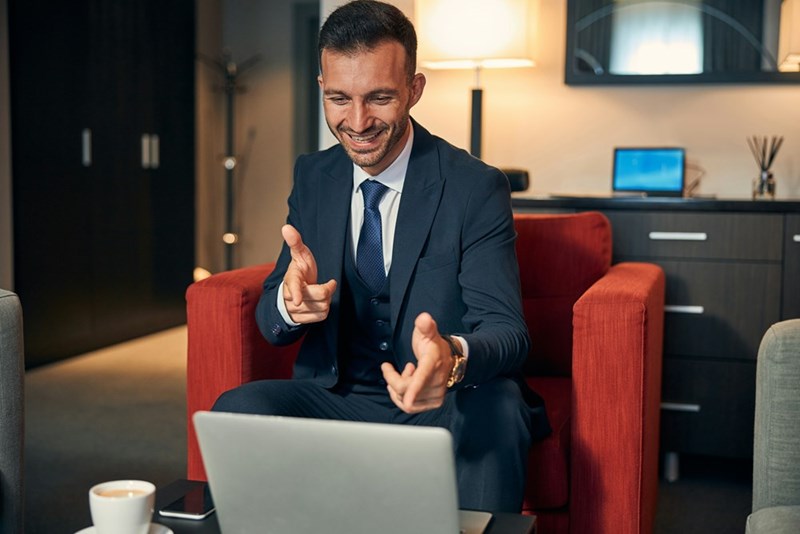 Young well-dressed professional business man smiling and pointing fingers to his laptop computer