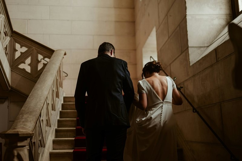 A bride and groom walk down the stairs at a coutrhouse