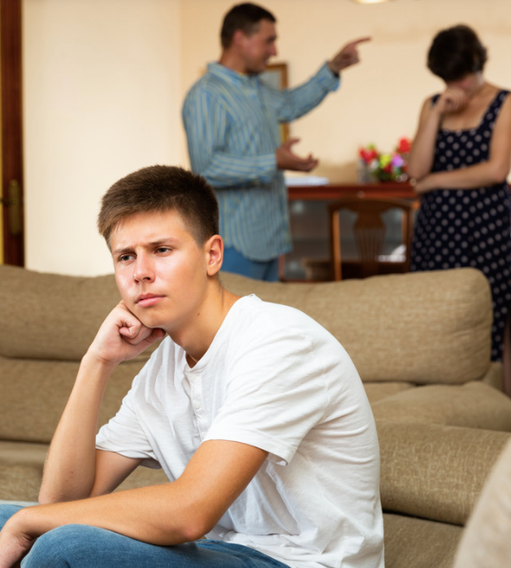 Teen boy listening to his parents argue in the background.