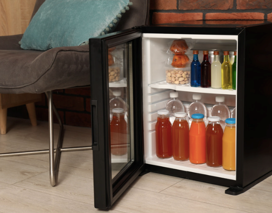 Mini fridge in the workplace full of drinks and snacks.