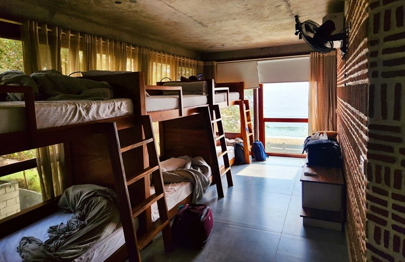 Shared hostel room with bunk beds and ocean view highlighting communal living and travel accommodation