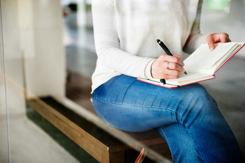 A woman writes something down in an agenda at her desk
