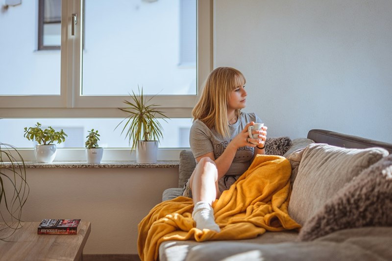 A woman sitting on the couch holding a cup of coffee, enjoying her quiet time at home
