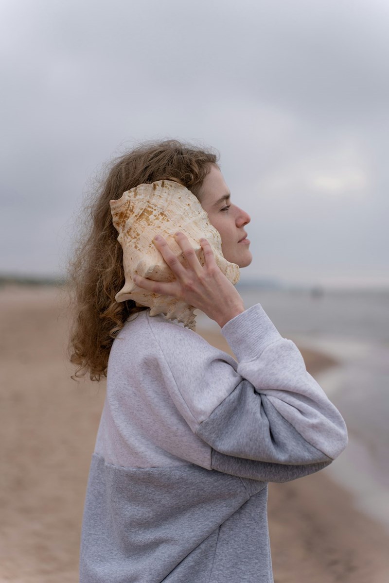 A woman holding a seashell up to her face
