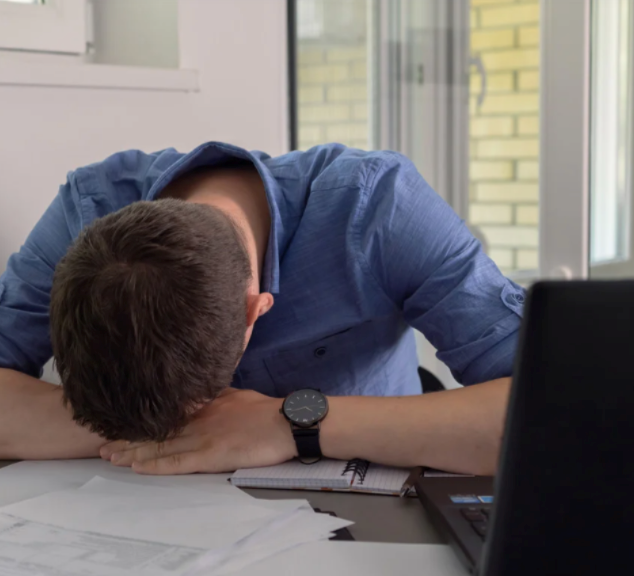 Burnt-out employee resting his head on his desk.