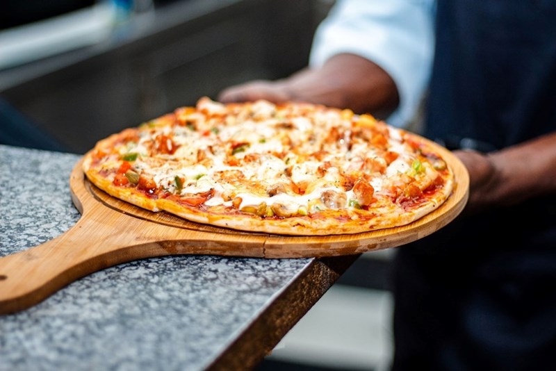 A pizza on a table is carefully removed by the owner