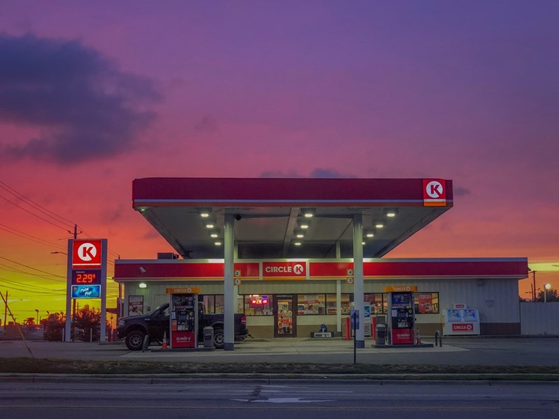 A glowing Circle K gas station at sunset with vibrant pink and purple skies.