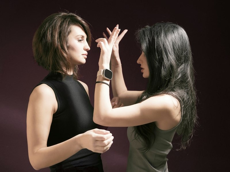 Two women facing each other in a dramatic, emotional interaction, highlighting tension, body language, and human connection in a studio portrait setting.