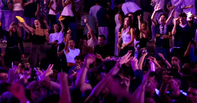 Numerous people dance in the crowd at a concert