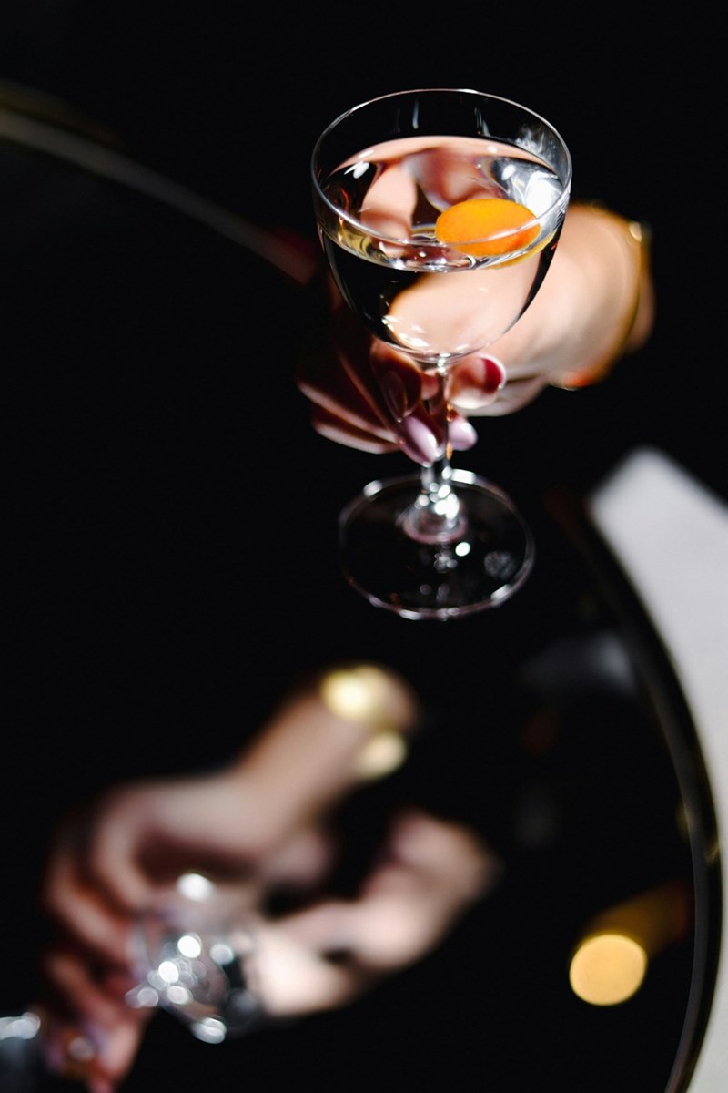 A woman's hand holding a cocktail against a dark background