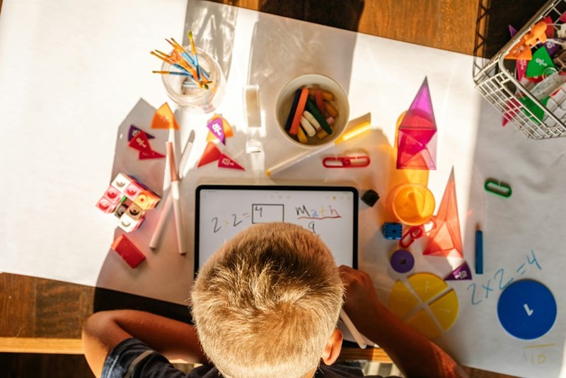 A young boy sitting at a table with a tablet