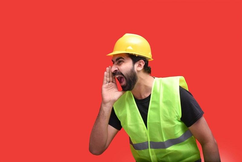 A man wearing a hard hat and holding a phone to his ear
