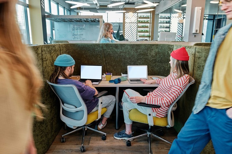 A couple of people sitting at a table with laptop