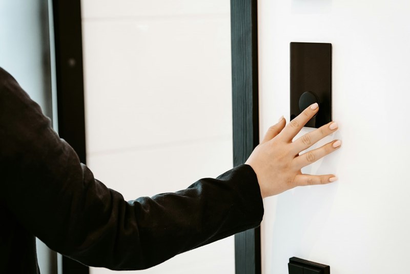 A person pressing a button on a white wall