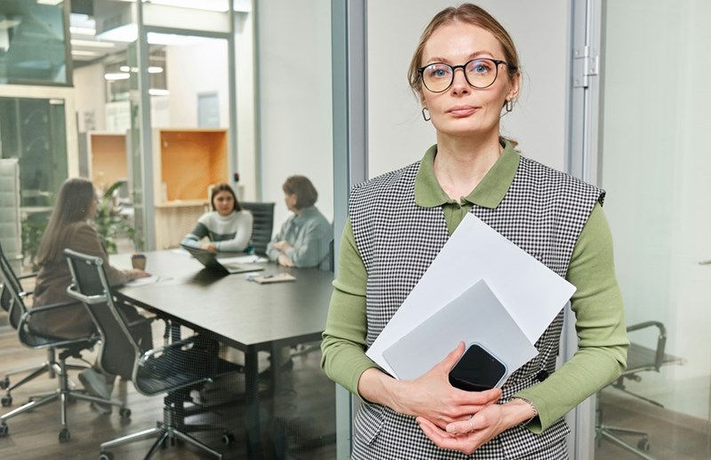A woman standing in an office building holding a piece of paper