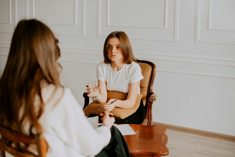 A woman sitting in a chair talking to another woman