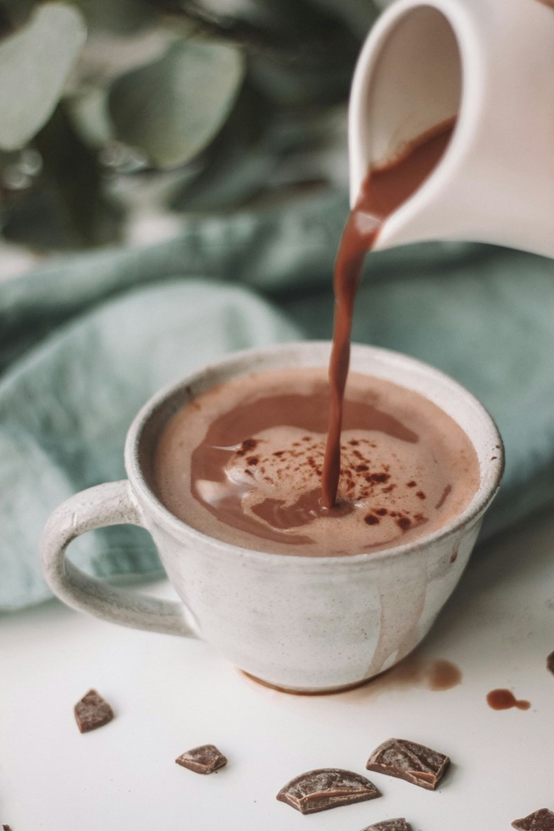 Chocolate being poured into a white mug.